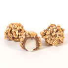 Three chocolate covered vanilla buttercreams with nuts on a white background